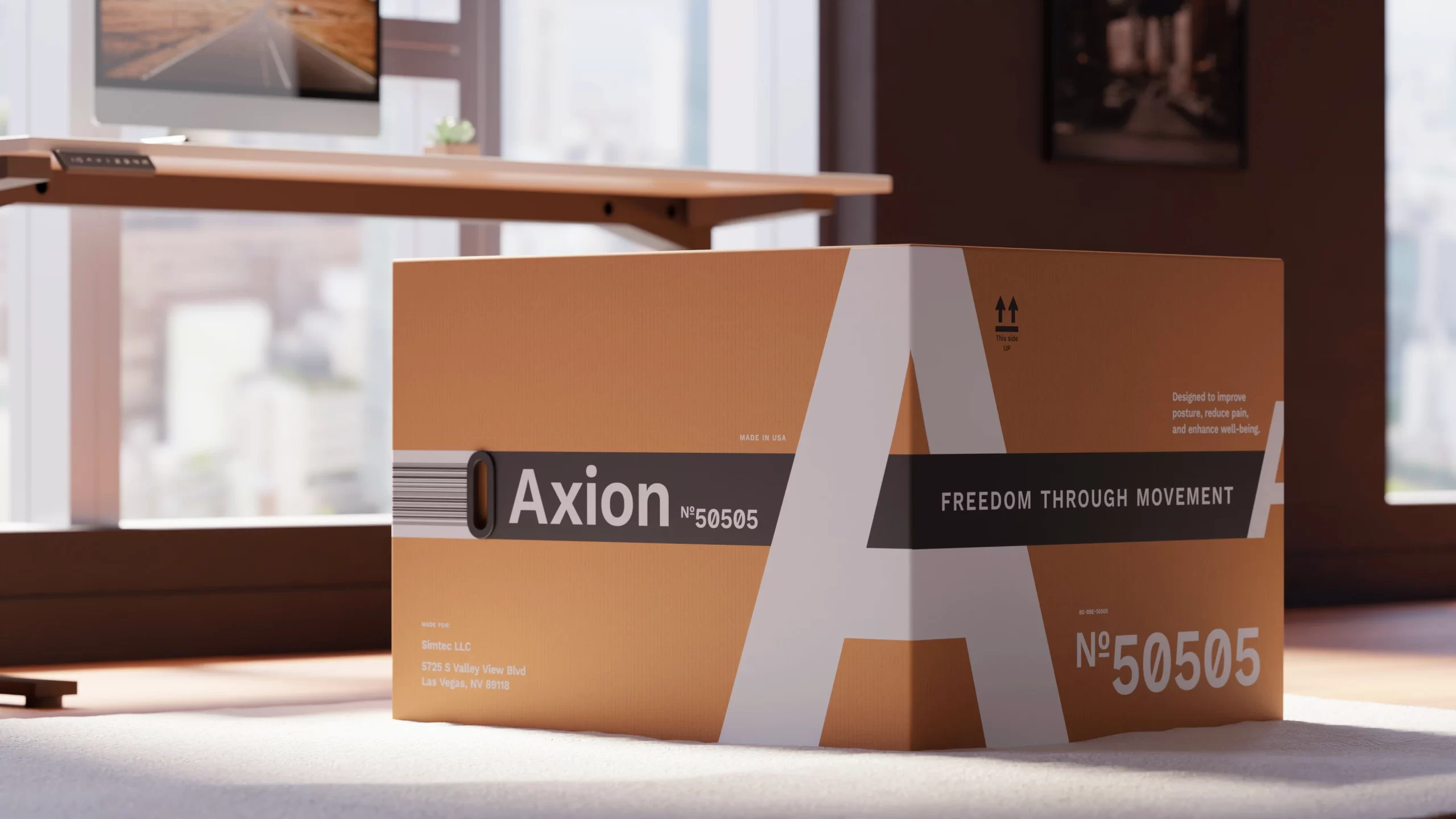 Warm earthy shipping box with an oversized white letter “A” wrapping the front and side. A dark horizontal band carries a barcode motif, the Axion logo, model “Nº 50505,” and the line “Freedom Through Movement.” Soft daylight in a modern office with New York city windows; clean, premium ergonomic-brand packaging.
