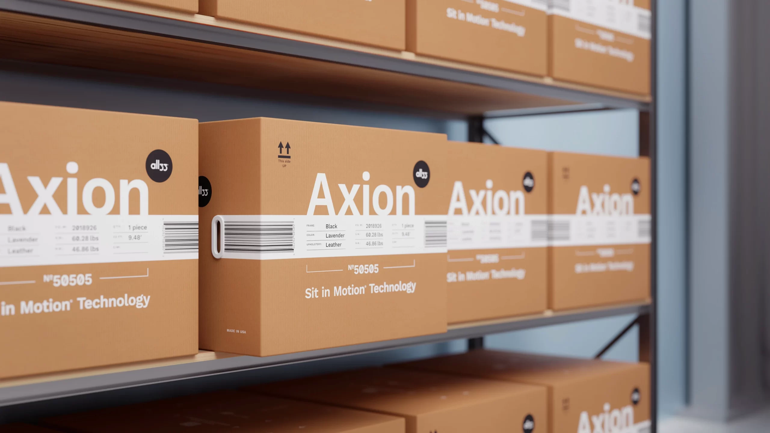 Warehouse shelving with rows of warm-earthy Axion shipping boxes. Each box has a crisp white specification band with barcode, large “Axion” wordmark, all33 logo, model number “Nº 50505,” and the line “Sit in Motion® Technology.” One box is pulled forward, showing a smooth plastic carry handle. The spec table lists frame, color, upholstery, and weight—easy to scan for inventory and fulfillment.